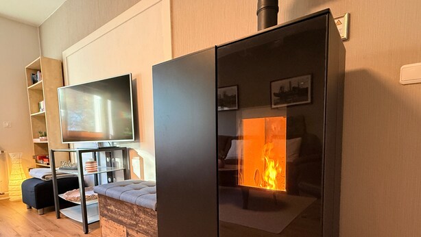 A modern living room with a flat-screen TV, a sofa, a glass-top coffee table, and a fireplace. - Apartment 'Glückauf' with Wi-Fi (Castrop-Rauxel)