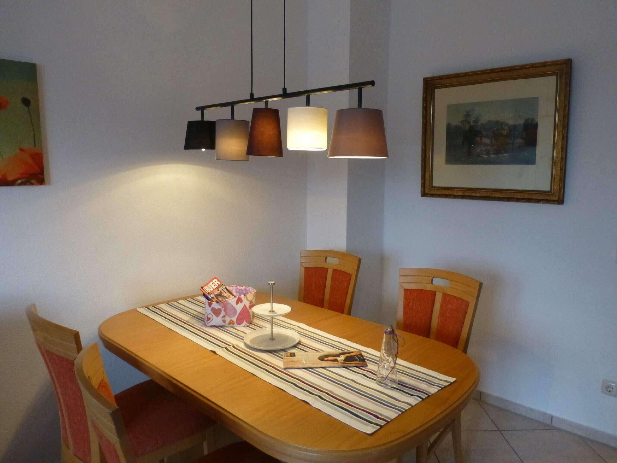 A dining area with a wooden table, striped tablecloth, and four chairs.