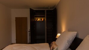 A bedroom with a bed, pillows, a wardrobe, and a nightstand.