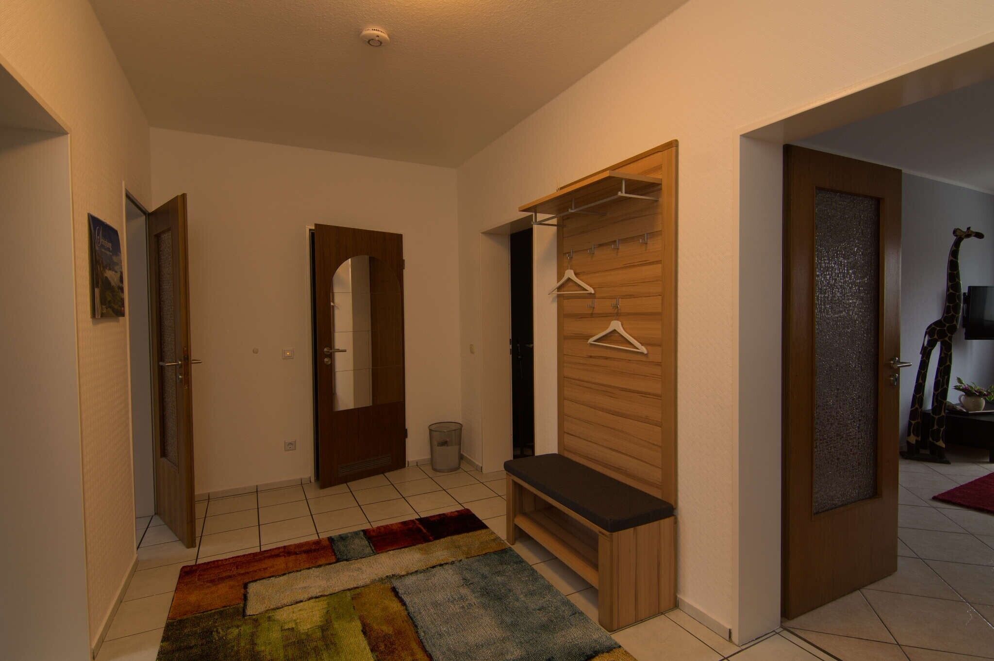 A hallway with a wooden bench, a coat rack, and a door with a mirror.
