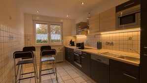 A modern kitchen with a built-in oven, microwave, and a large window with a view of trees.