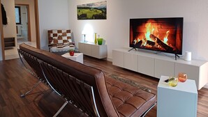 Een moderne woonkamer met een leren bank, een flatscreen-tv, een open haard en een schilderij aan de muur.