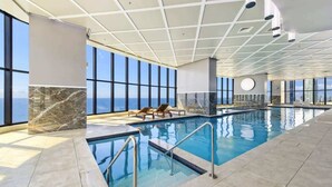 Una piscina interior con vistas despejadas del horizonte urbano a través de amplios ventanales.