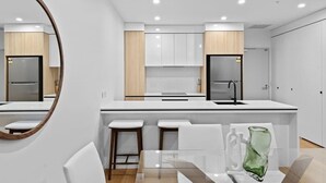 Une cuisine moderne avec des meubles blancs, un îlot central et des tabourets de bar.
