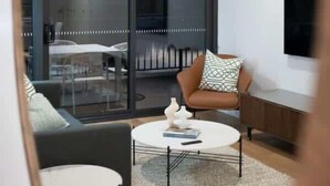 Un salon moderne avec un canapé, une table basse et un téléviseur fixé au mur.
