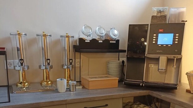 Una estación de café con dispensadores, una máquina de café y una variedad de tazas y vasos.