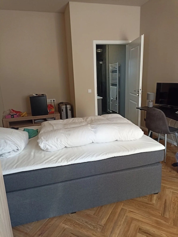 Une chambre à coucher avec un lit, un bureau avec un ordinateur, une télévision et une armoire.