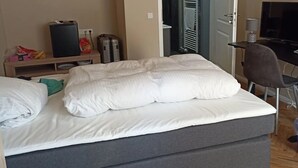 Ett sovrum med en säng, ett skrivbord med en dator, en tv och en garderob.
