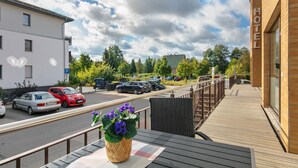Un balcón de hotel con vista a coches estacionados y un edificio con la inscripción 'HOTEL' al fondo.