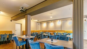 Un salón de conferencias con mesas, sillas, un proyector y una pantalla grande.