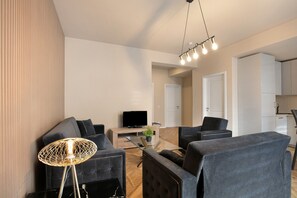 Un salon moderne avec un canapé, des fauteuils, une table basse et un téléviseur.