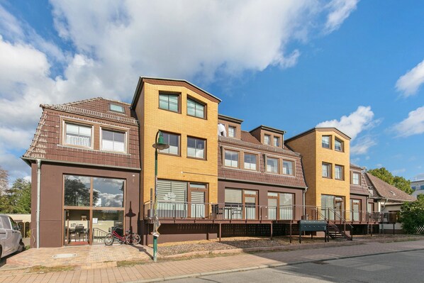 A row of modern residential buildings with large windows, a bike parked outside, and a clear sky.