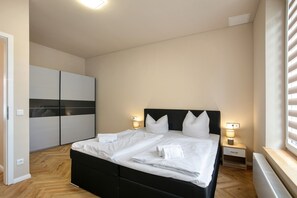 A bedroom with a bed, bedside tables, a wardrobe, and a radiator.