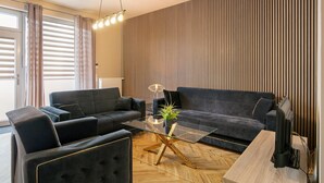 Una sala de estar moderna con una mesa de centro de vidrio, dos sofás, un televisor y piso de madera.