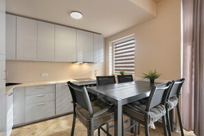 Une cuisine moderne avec une table et des chaises, une fenêtre avec des stores et une plante en pot.