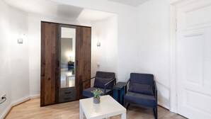 A room with a wooden wardrobe, two grey chairs, a white table, and a potted plant. - Apartment "Vogelsberger Bett 5 Die 2 Links" with Wi-Fi (Alsfeld)
