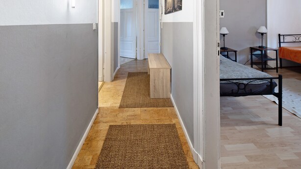 Un couloir avec un banc, un lit et un bureau avec des lampes.