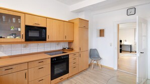 Une cuisine moderne avec des meubles en bois, un four à micro-ondes, un four traditionnel et une table en verre.