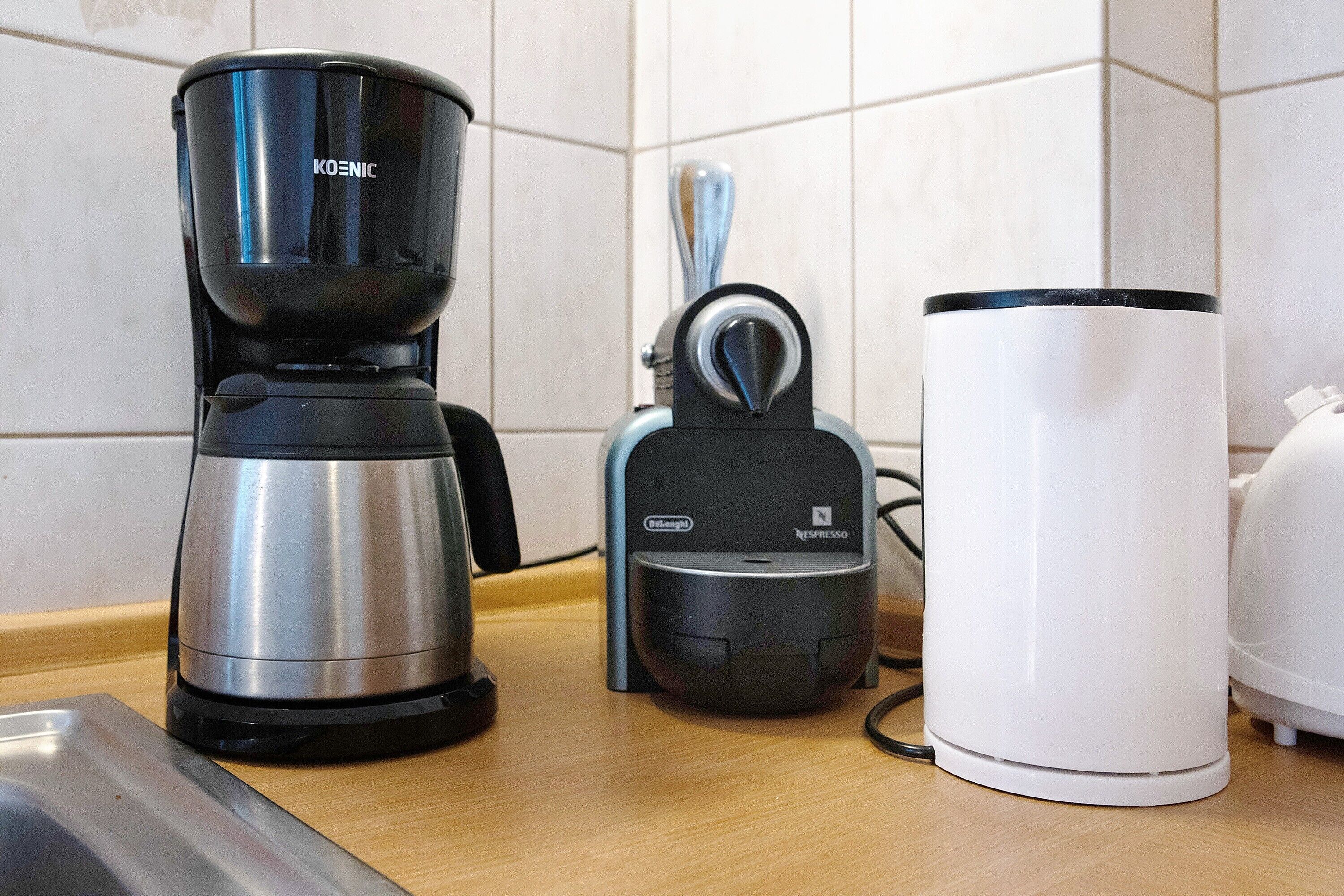 Eine Kaffeemaschine, eine Keurig und eine weiße Kaffeemaschine auf einer Küchenarbeitsplatte.