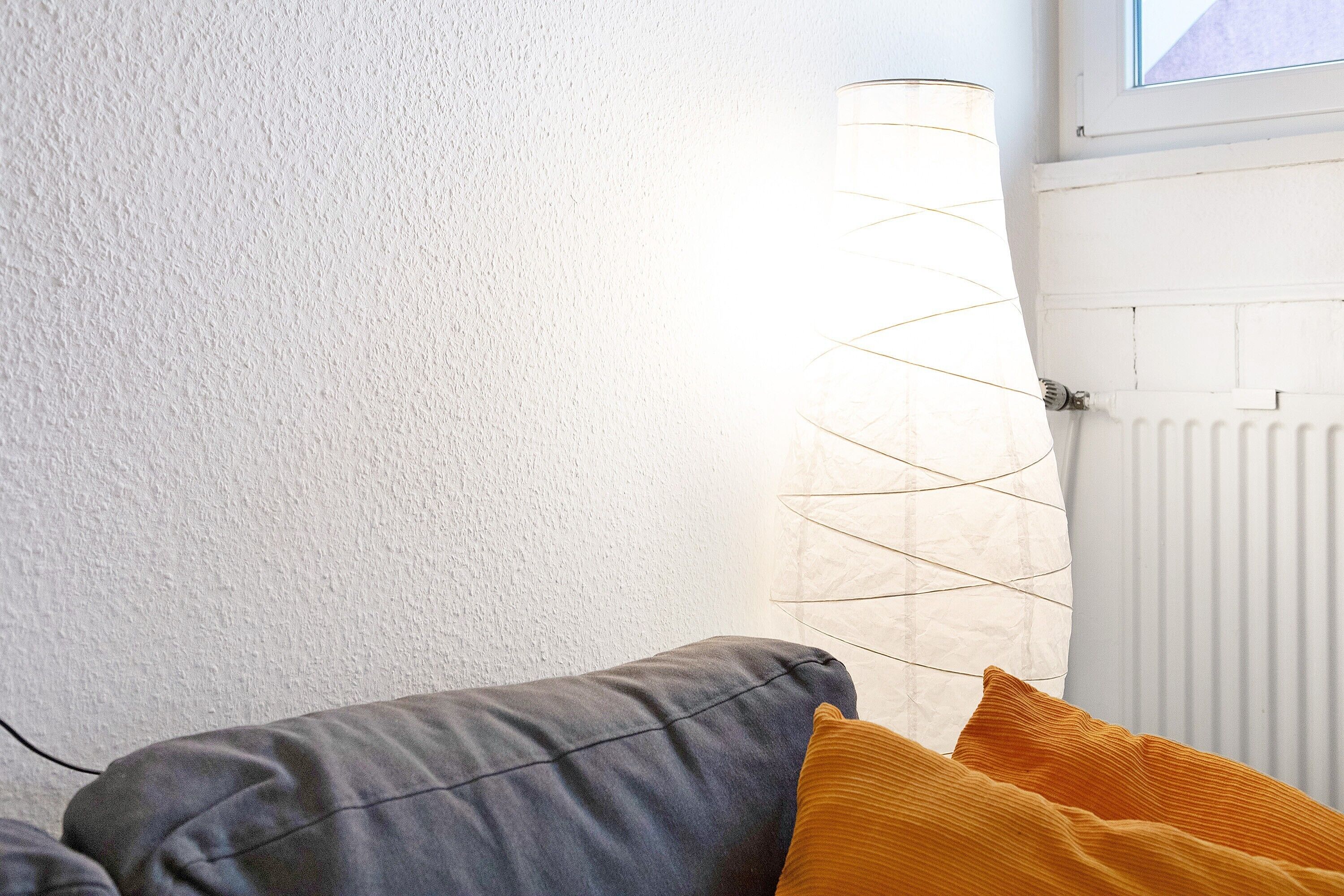 Una habitación con pared blanca texturizada, un radiador y una lámpara de diseño en espiral.