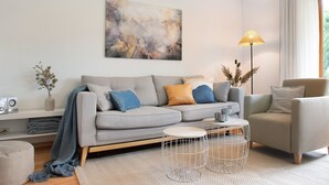 Un salon moderne avec un canapé gris, une table basse, un lampadaire et un tableau accroché au mur.