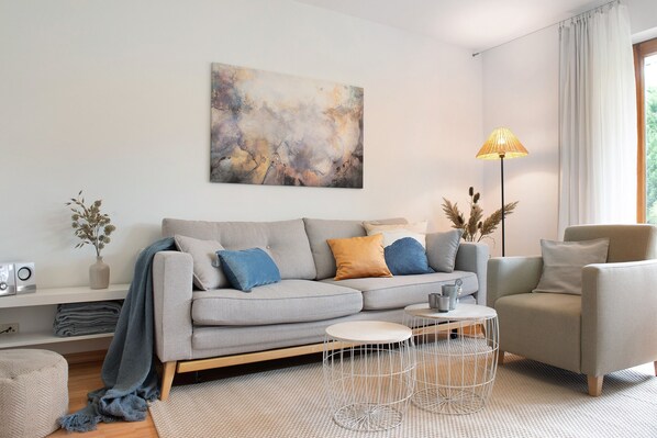 A modern living room with a grey sofa, a coffee table, a floor lamp, and a painting on the wall.