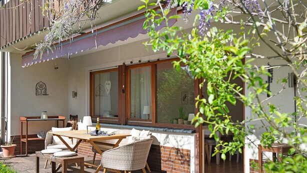 Un espace extérieur aménagé pour les repas, avec une table, des chaises et un mur en briques.