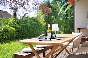 An outdoor wooden table with a bottle of wine, glasses, and a napkin.