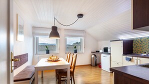 Een moderne keuken met houten vloeren, een eethoek met een bank, en een uitzicht door grote ramen.