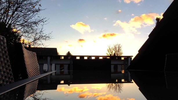 Een binnenplaats met een heldere lucht en wolken die in het water worden weerspiegeld.