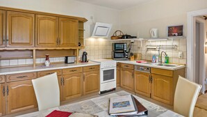 Una cocina con armarios de madera, estufa, microondas y comedor con mesa y sillas.