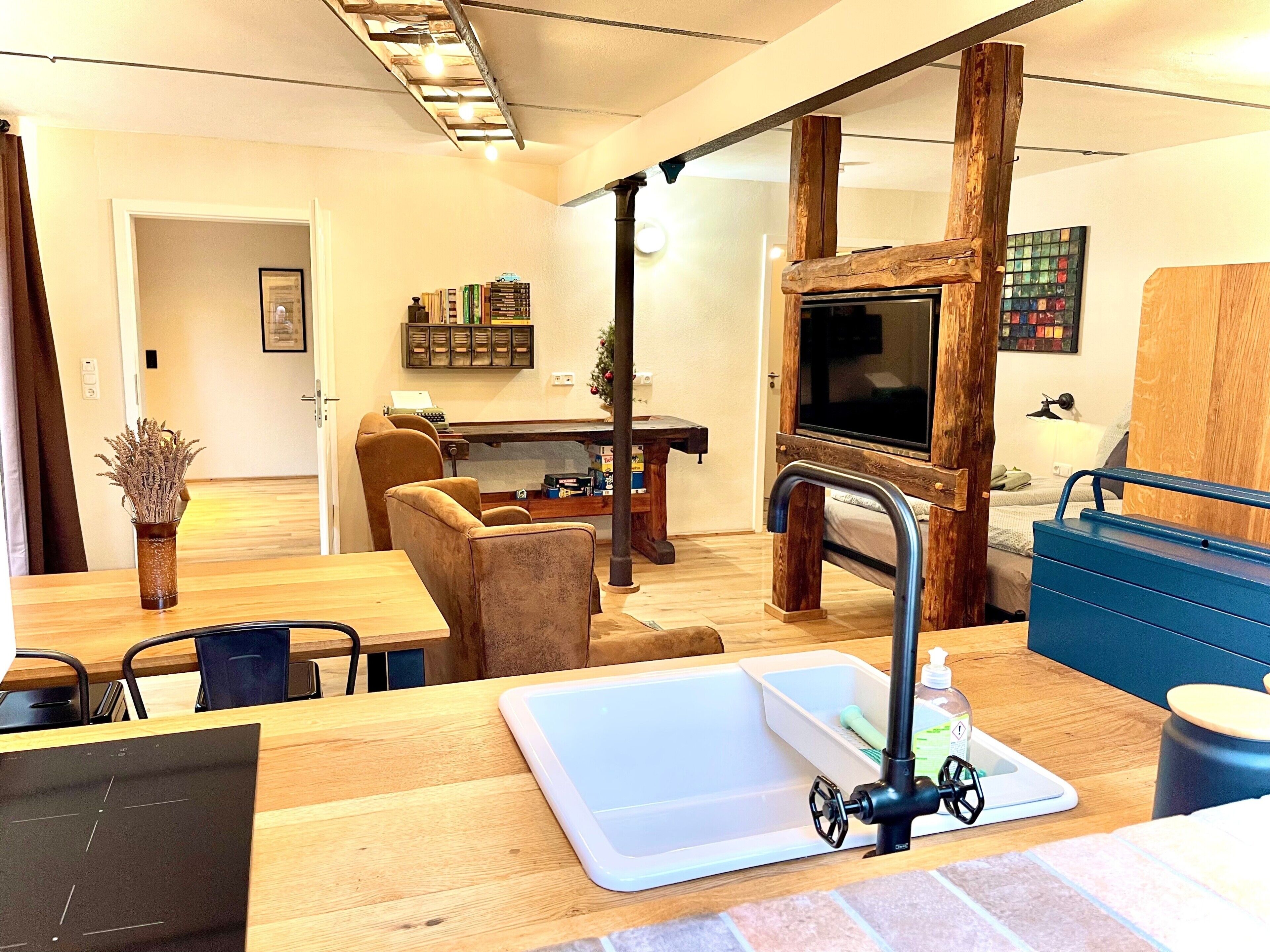 Un salon moderne avec une table à manger en bois, un canapé, un téléviseur et un meuble de rangement bleu.