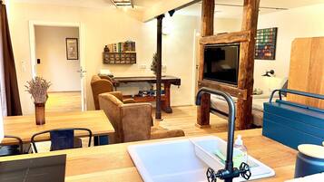 Un salon moderne avec une table à manger en bois, un canapé, un téléviseur et un meuble de rangement bleu.