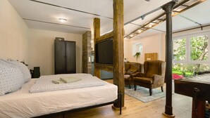 Un dormitorio con cama, televisor, armario y una silla.