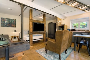 Una habitación con una cama, televisión, una silla de madera, un escritorio y una ventana.