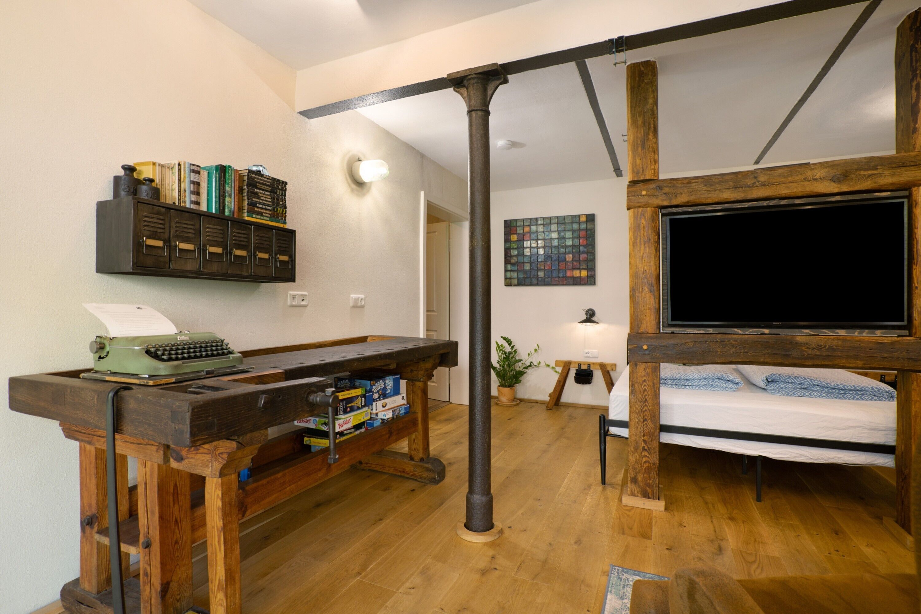 Une pièce comprenant un bureau en bois, un lit, une télévision et une bibliothèque.