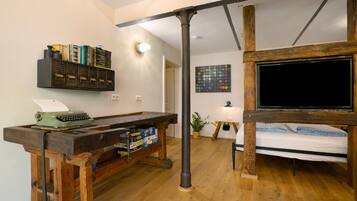 Une pièce comprenant un bureau en bois, un lit, une télévision et une bibliothèque.