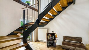 Eine Treppe mit Holzboden und schwarzen Geländern, ein Heizkörper und eine Bank mit Stauraum.