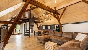 Ein großzügiges Loft mit einer Holztreppe, einem großen Ecksofa und einem Essbereich.