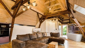 Ein Loft-Wohnzimmer mit Holzboden, einem Ecksofa, einem Couchtisch aus Holz und einer modernen Badewanne.