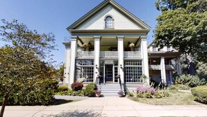 Une maison à deux étages avec une entrée centrale, des colonnes et un balcon.