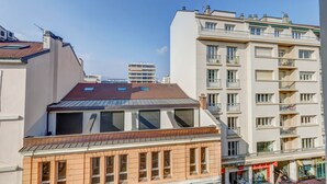 Un immeuble résidentiel à plusieurs étages, doté de balcons et d’un toit plat.