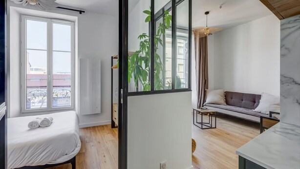 Un salon moderne avec un canapé, une table à manger et une grande fenêtre.
