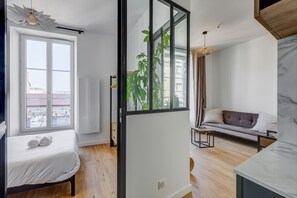 Una sala moderna con sofá, mesa de comedor y un ventanal grande.
