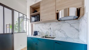 Une cuisine moderne avec des armoires de couleur turquoise, un dosseret en marbre et un micro-ondes encastré.
