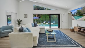 Una sala de estar moderna con un sofá, una mesa de centro y vista a una piscina.