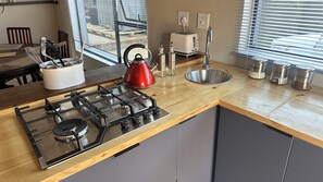 A modern kitchen with a gas stove, kettle, toaster, and stainless steel sink.