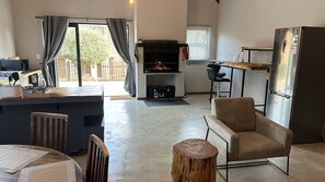 Una cocina moderna con una parrilla empotrada, una zona de comedor con mesa y sillas de madera, y un refrigerador grande.