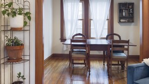Un comedor con mesa y sillas de madera, una planta en maceta y un sofá azul.