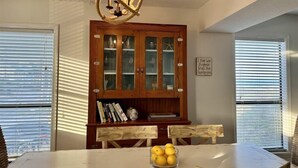 A dining area with a round table, wooden chairs, a glass cabinet with books, and a chandelier. - Amelia Island 2 Bedroom Oceanfront Private Home (Fernandina Beach)